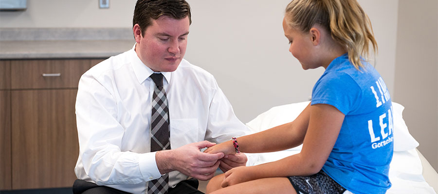 Image of doctor tending to young girls wrist.