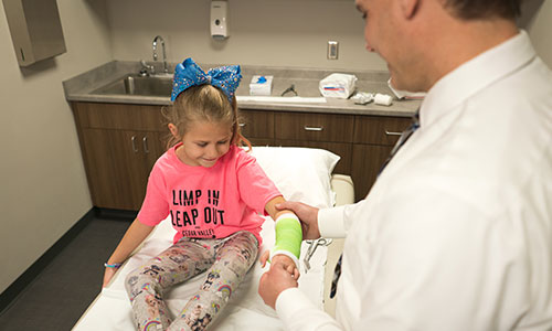 Image of doctor tending to young girl's arm cast.